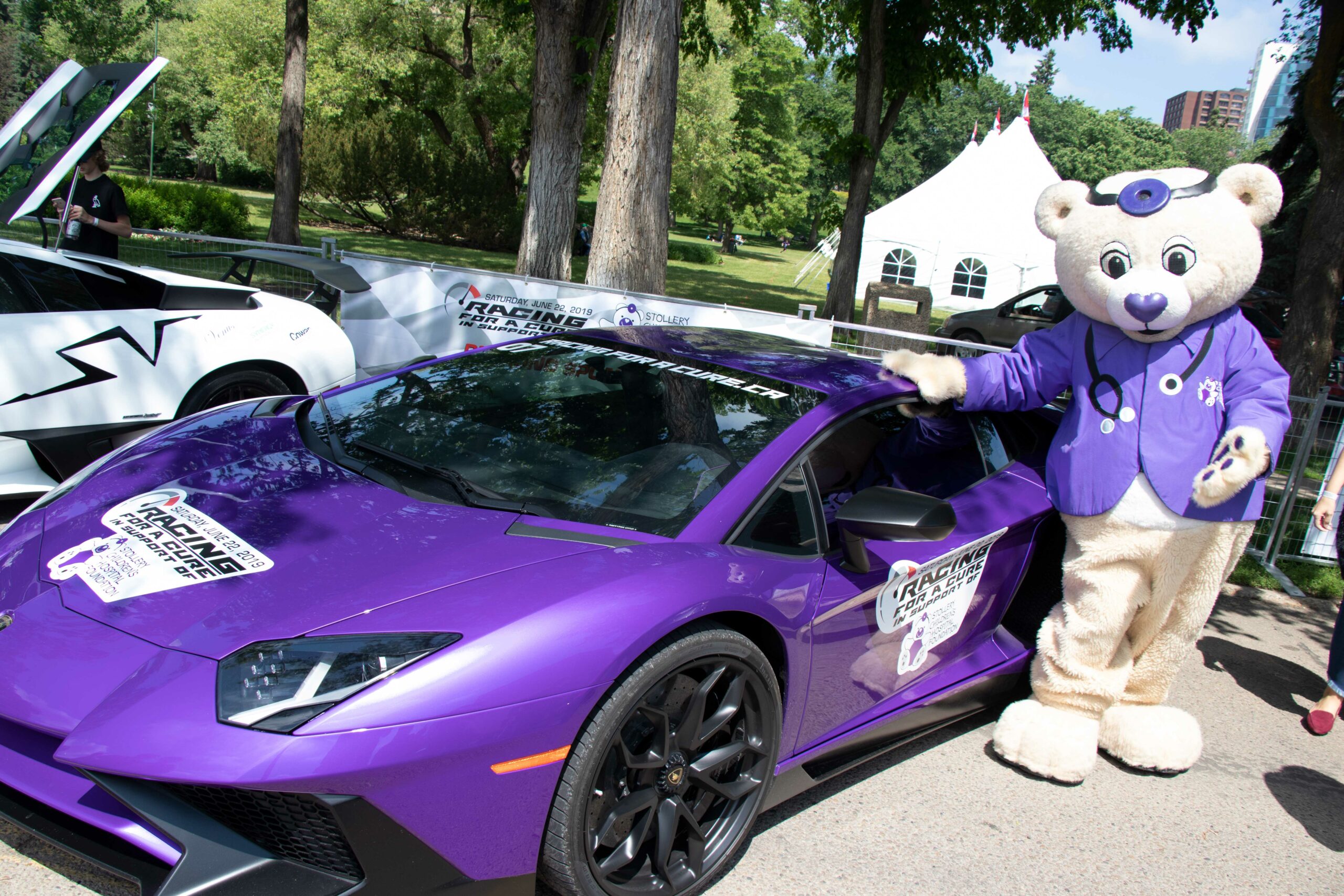 dr patchup standing next to purple sports car at racing for a cure event