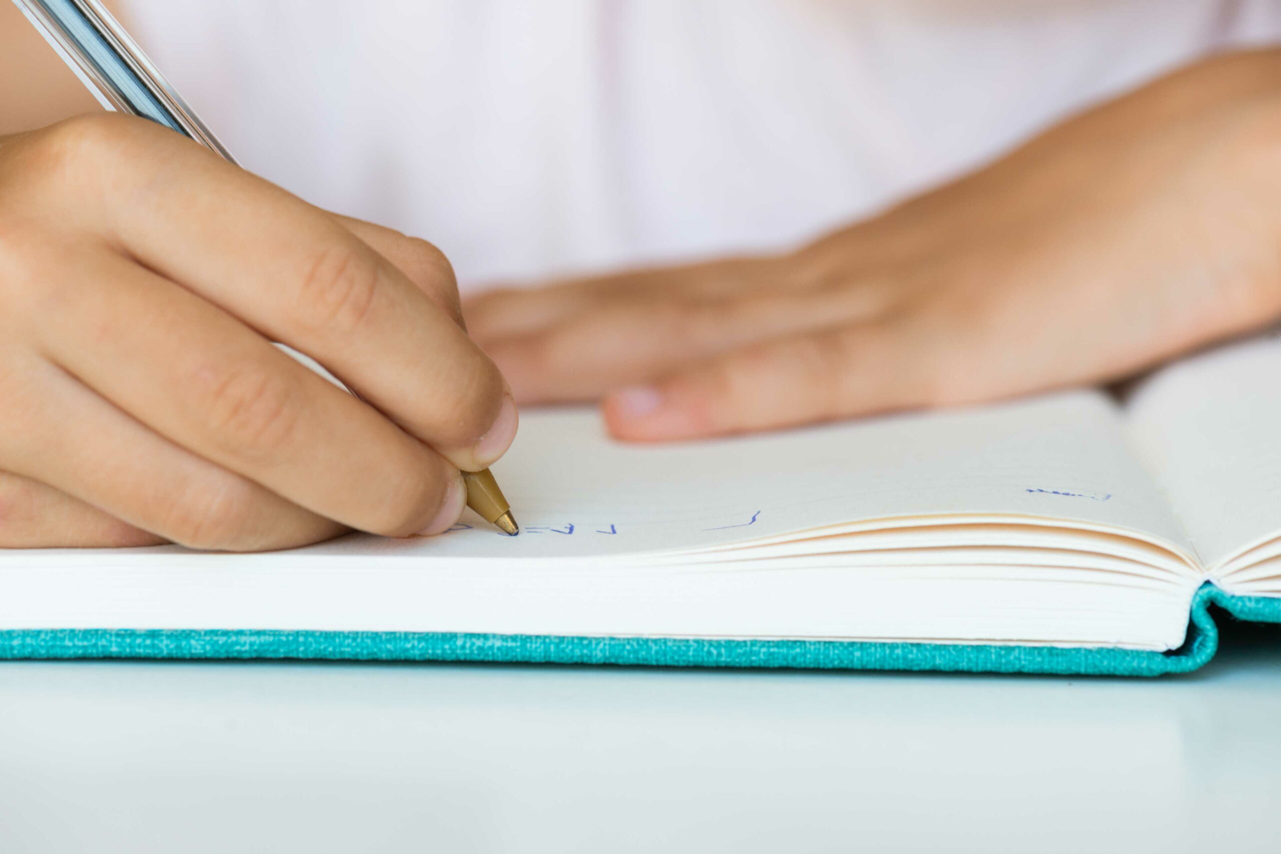 closeup of a child writing in book with a pen