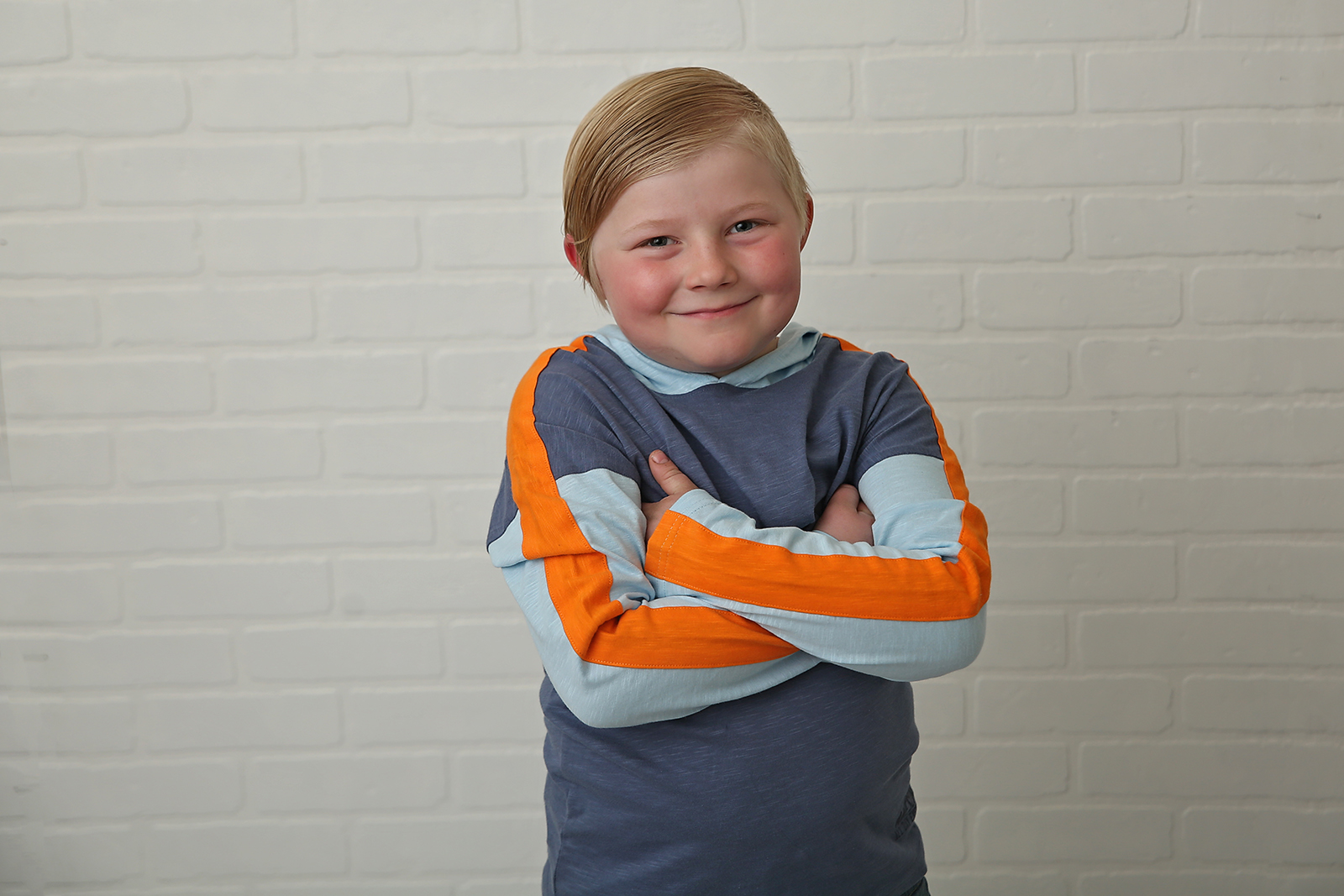 stollery kid tucker arms crossed against brick wall