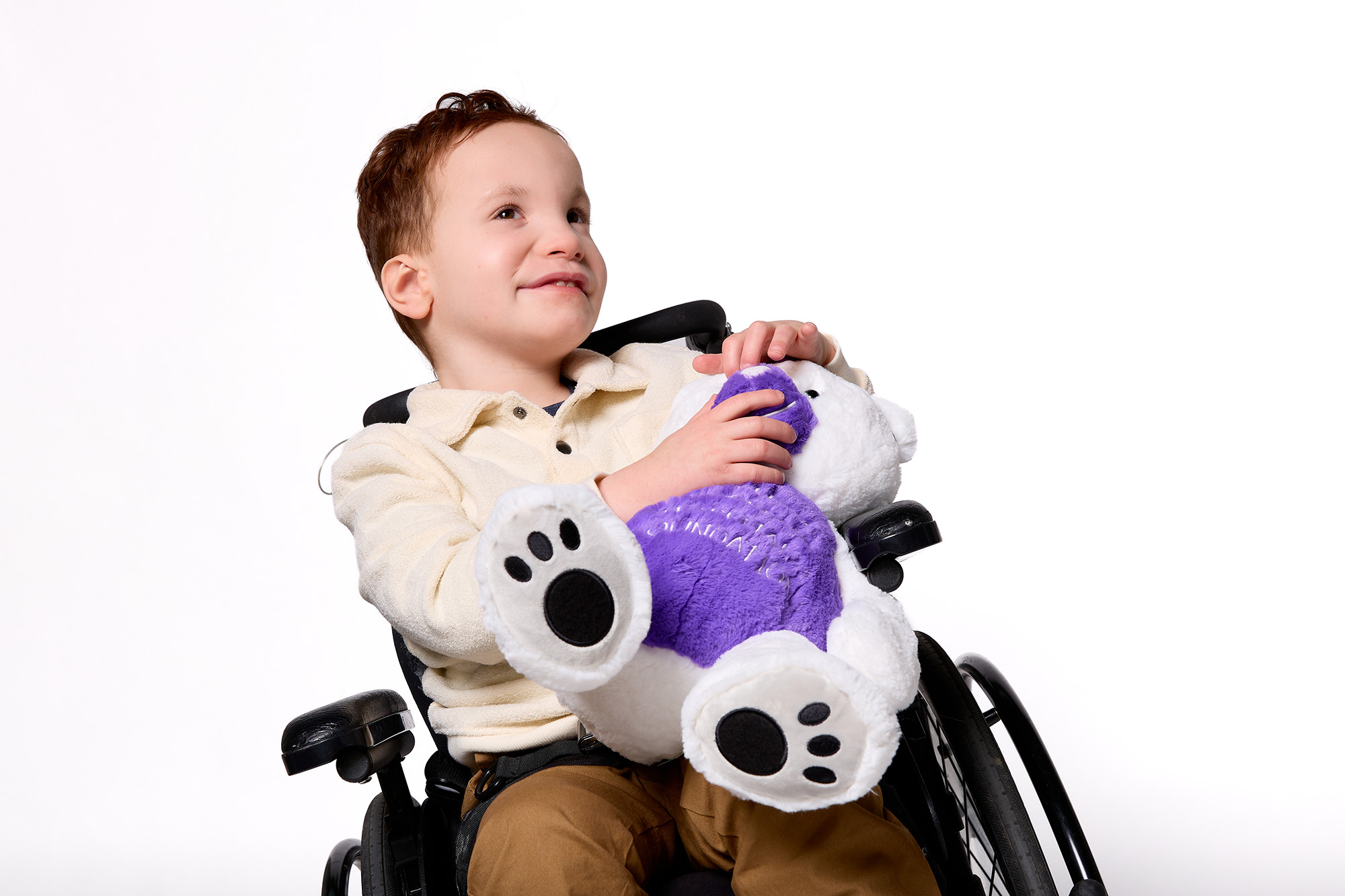 Stollery squad kid Beau in his wheelchair holding a Stollery Dr. PatchUp plush bear