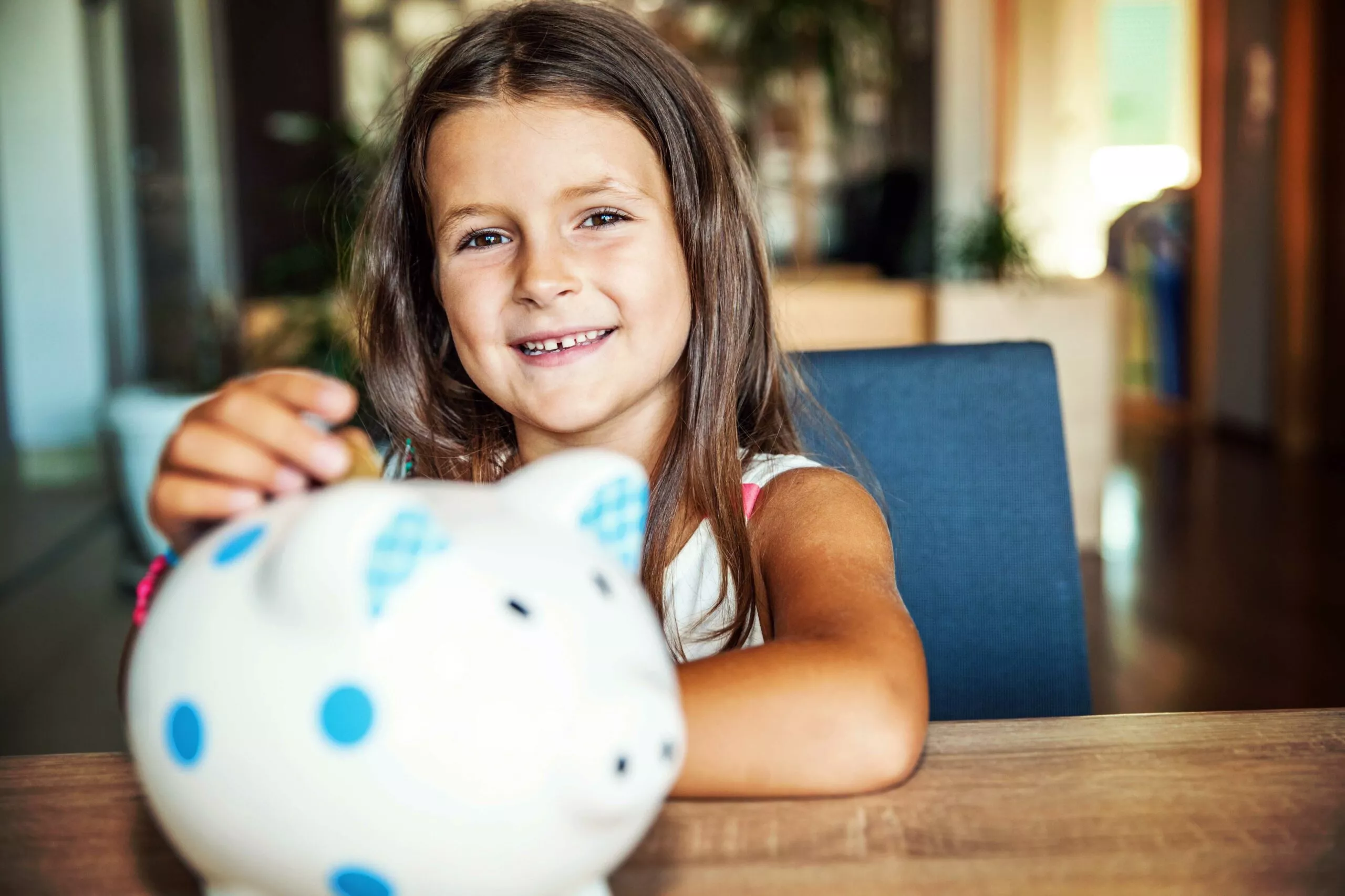 child smiling with ceramic piggy bank on table