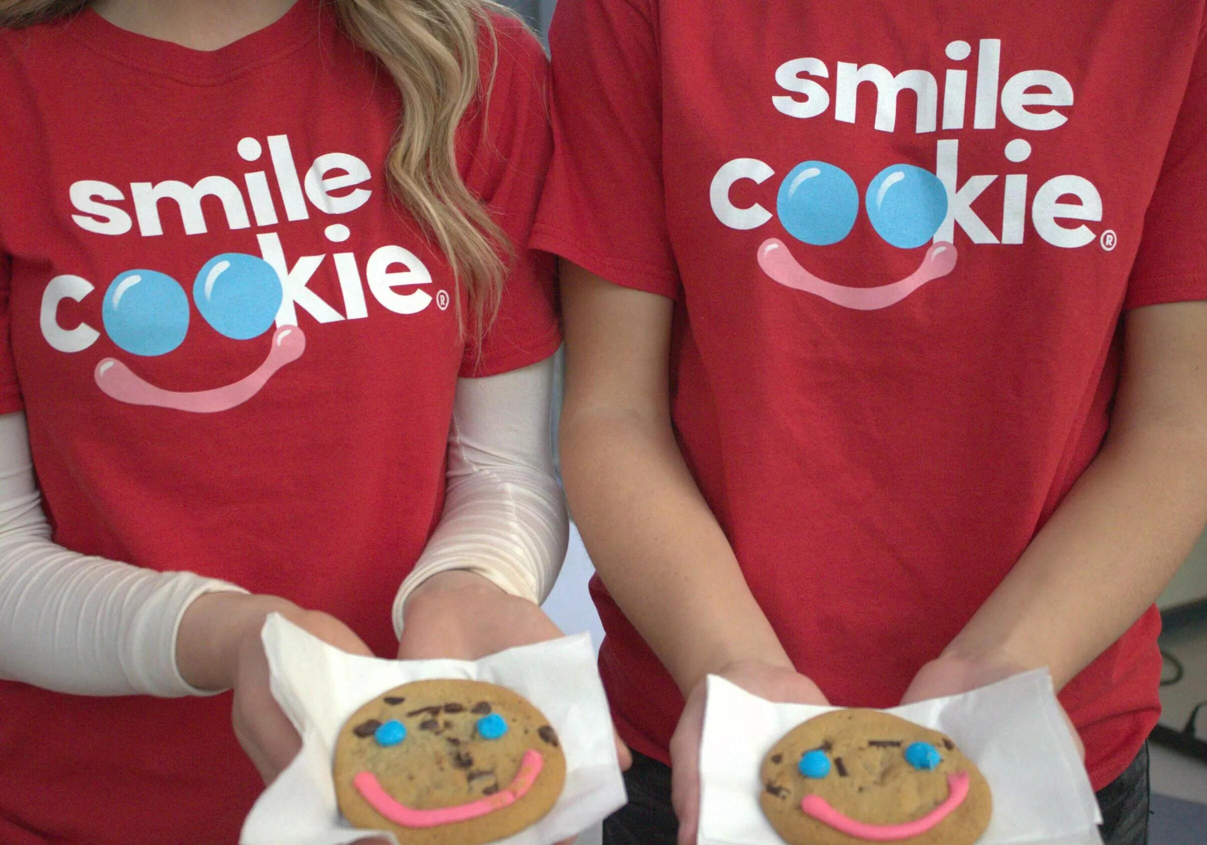 two volunteers holding tim hortons smile cookies